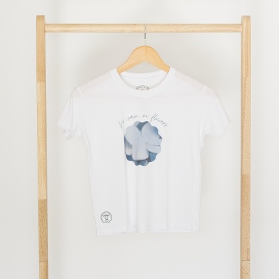 T-shirt branca com estampado azul e texto pendurada em cabide de madeira