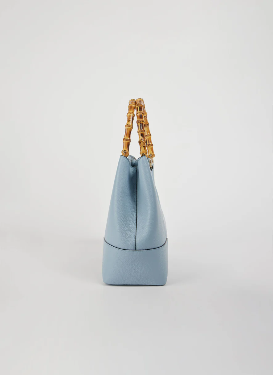 MALA EM PELE ITALIANA AMALFI AZUL CELESTE | TUSCAN Mala de mão azul clara com alças de bambu em fundo branco