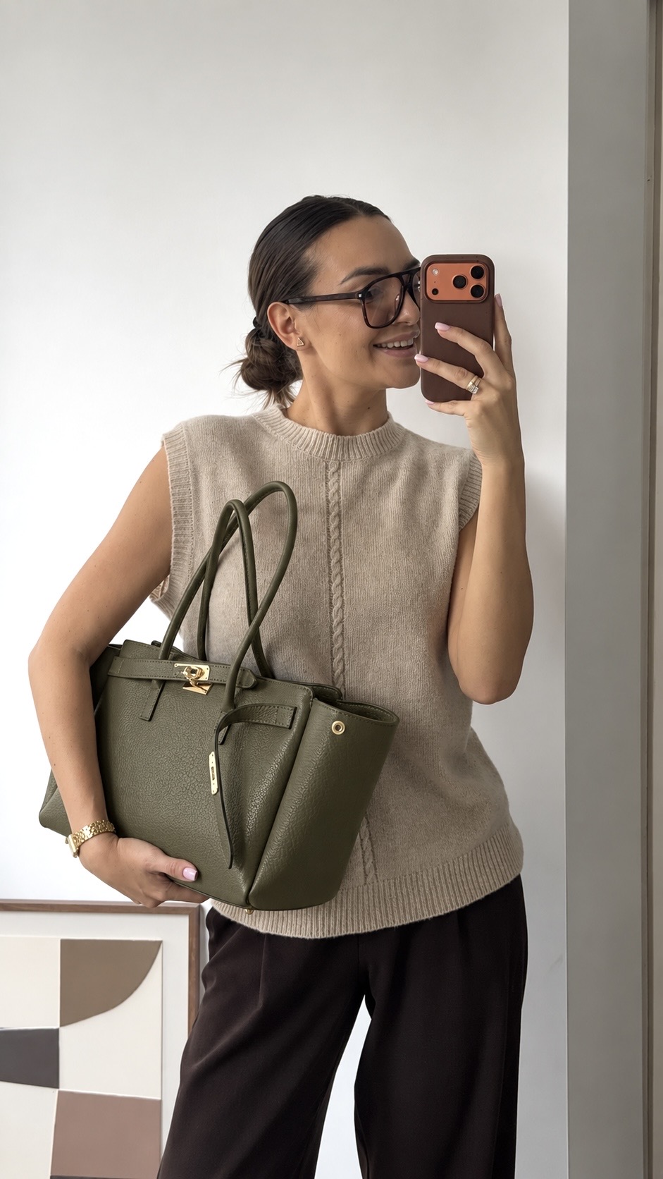 MALA EM PELE ITALIANA PADOVA VERDE OLIVE | TUSCAN Mulher com mala verde em pele, camisola bege de malha e óculos a tirar selfie