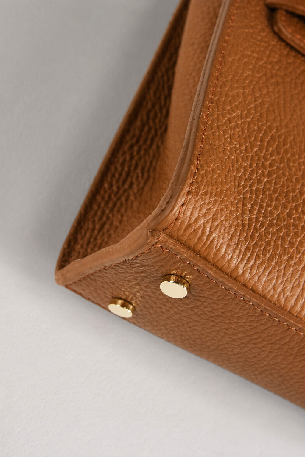 MALA EM PELE ITALIANA FERRARA CONHAQUE | TUSCAN Canto inferior de mala ou bolsa em pele castanha com bases metálicas douradas