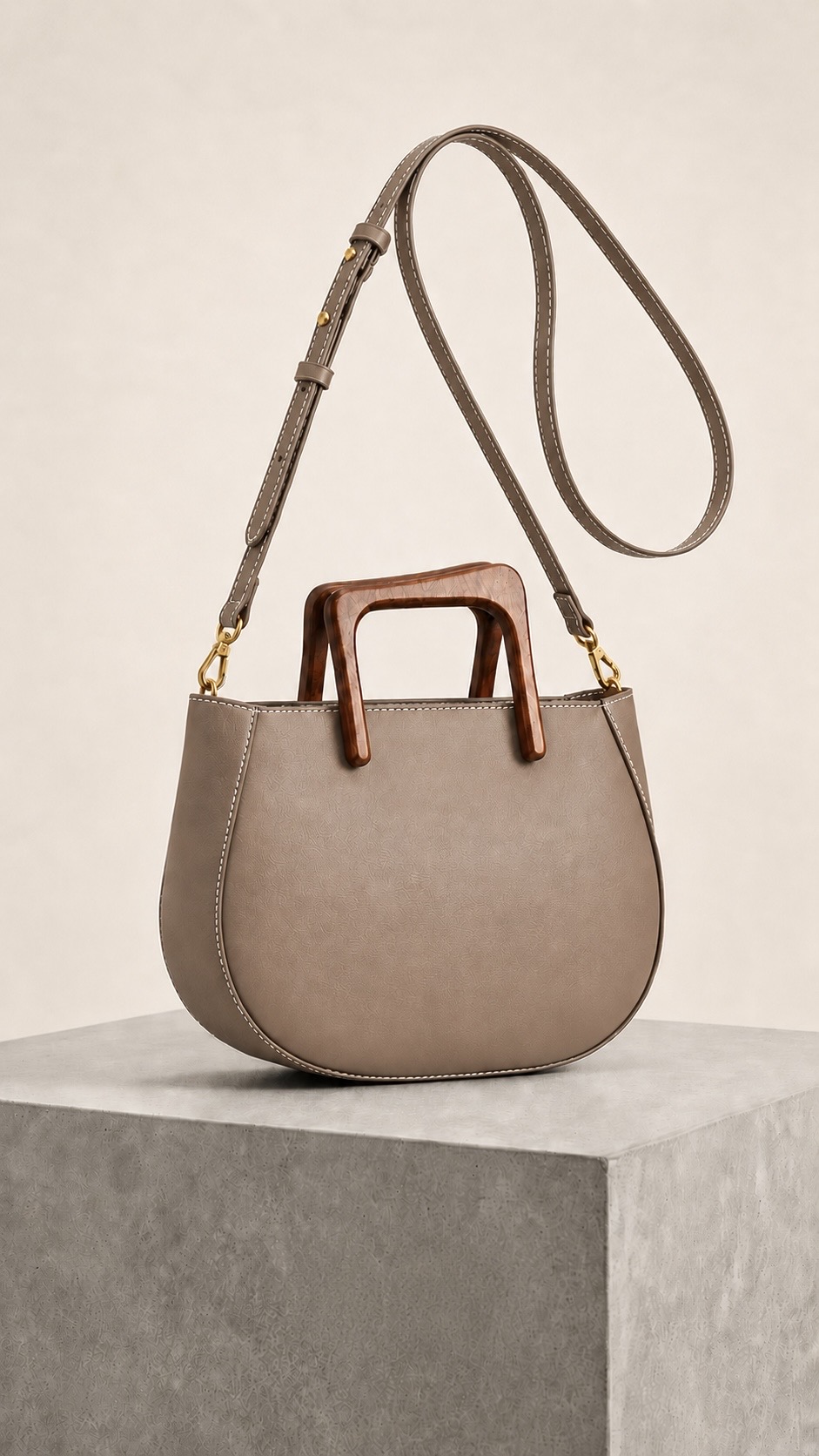 MALA EM PELE ITALIANA NÁPOLES TAUPE | TUSCAN Mala taupe com alças castanhas e tiracolo ajustável sobre pedestal cinza