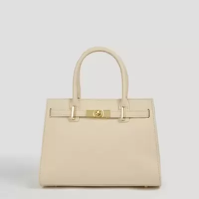 Mala de mão bege clara com fecho dourado sobre fundo cinzento