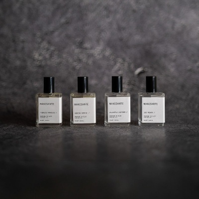 Quatro frascos de perfume quadrados com tampas pretas e etiquetas brancas da marca MANSANTE.