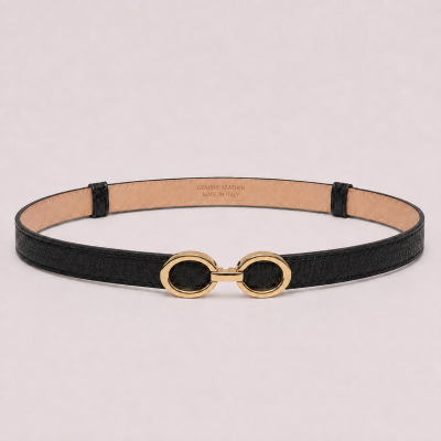 Cinto preto fino com fivela dourada oval sobre fundo rosa claro