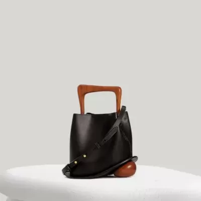Bolsa preta com alças de madeira castanha sobre base branca