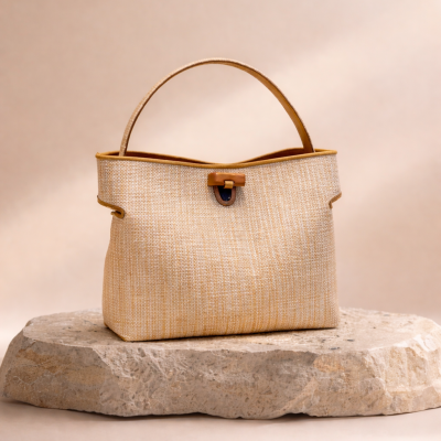 Mala de mão bege com detalhes castanhos sobre pedra clara