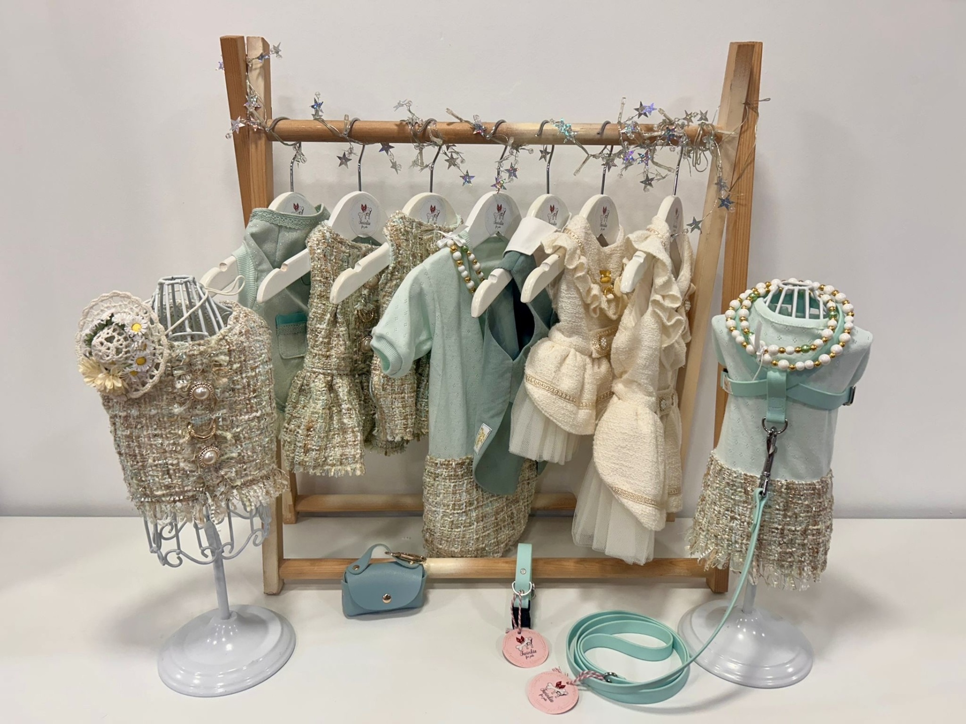 Roupas em miniatura para bonecas com acessórios expostas em cabide de madeira e manequins