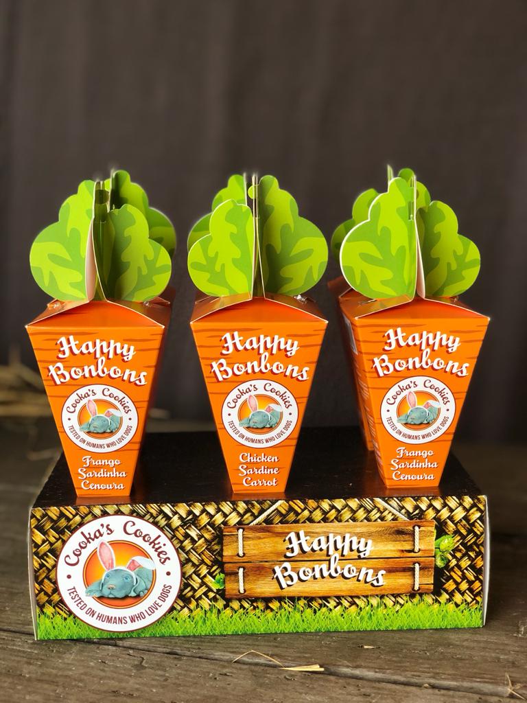 Embalagens em forma de cenoura com etiquetas 'Cooka's Cookies' e base decorativa de madeira e relva
