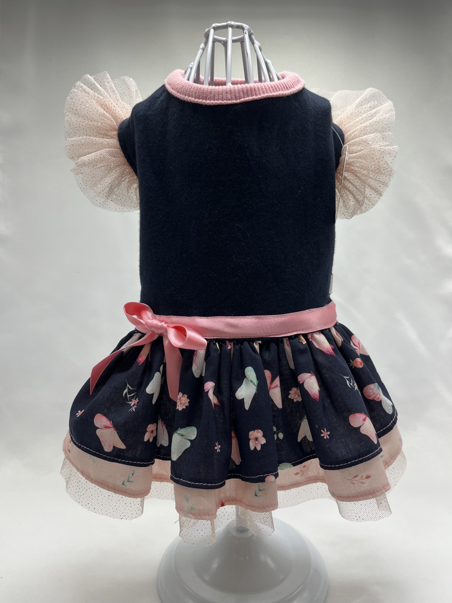 Vestido azul escuro com gola rosa, mangas de tule creme e saia com padrão de borboletas e flores