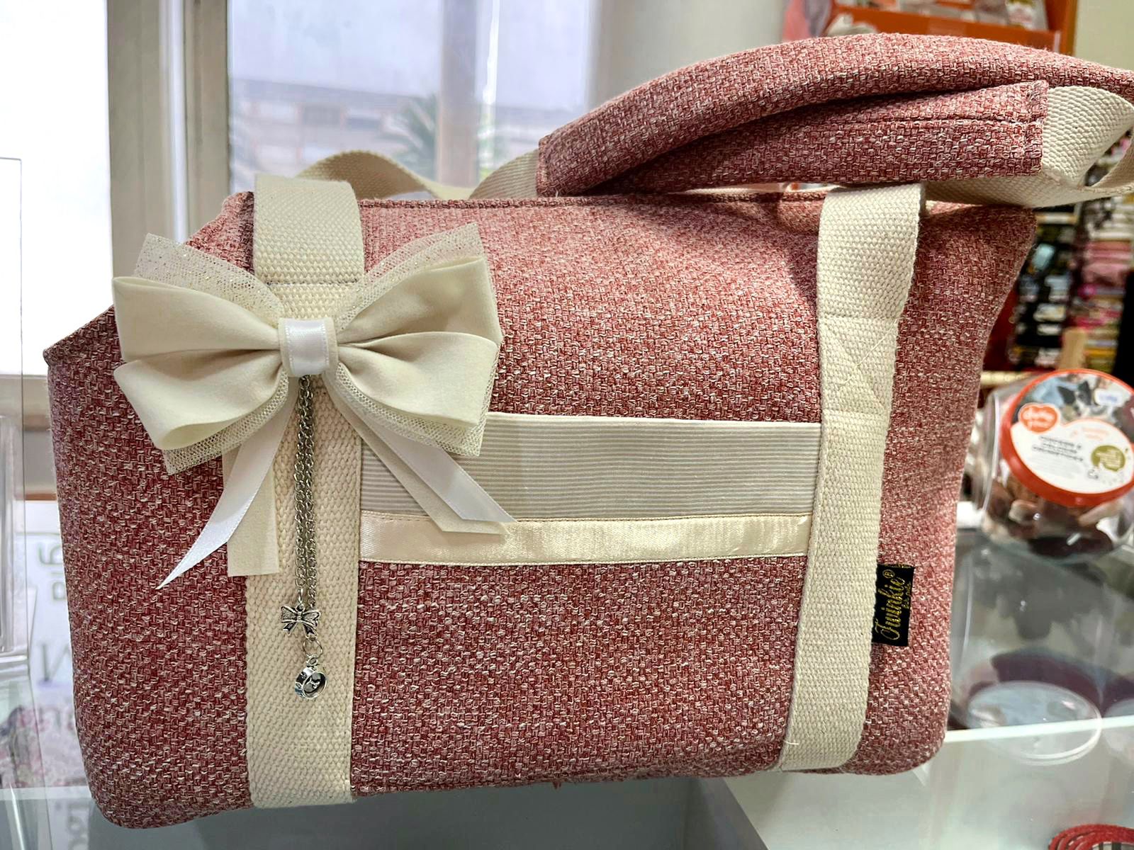 Bolsa cor de rosa com alças e laço branco decorativo numa superfície de vidro