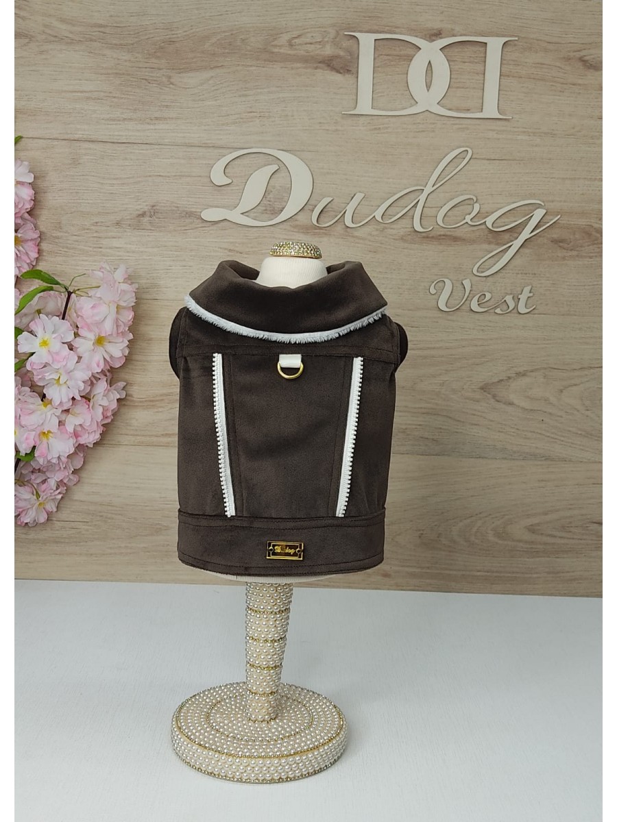 Colete castanho para cão com detalhes brancos e argola dourada num suporte decorado com pérolas