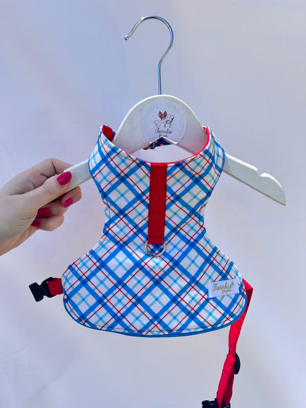 Peitoral de cão xadrez azul, vermelho e branco pendurado em cabide branco