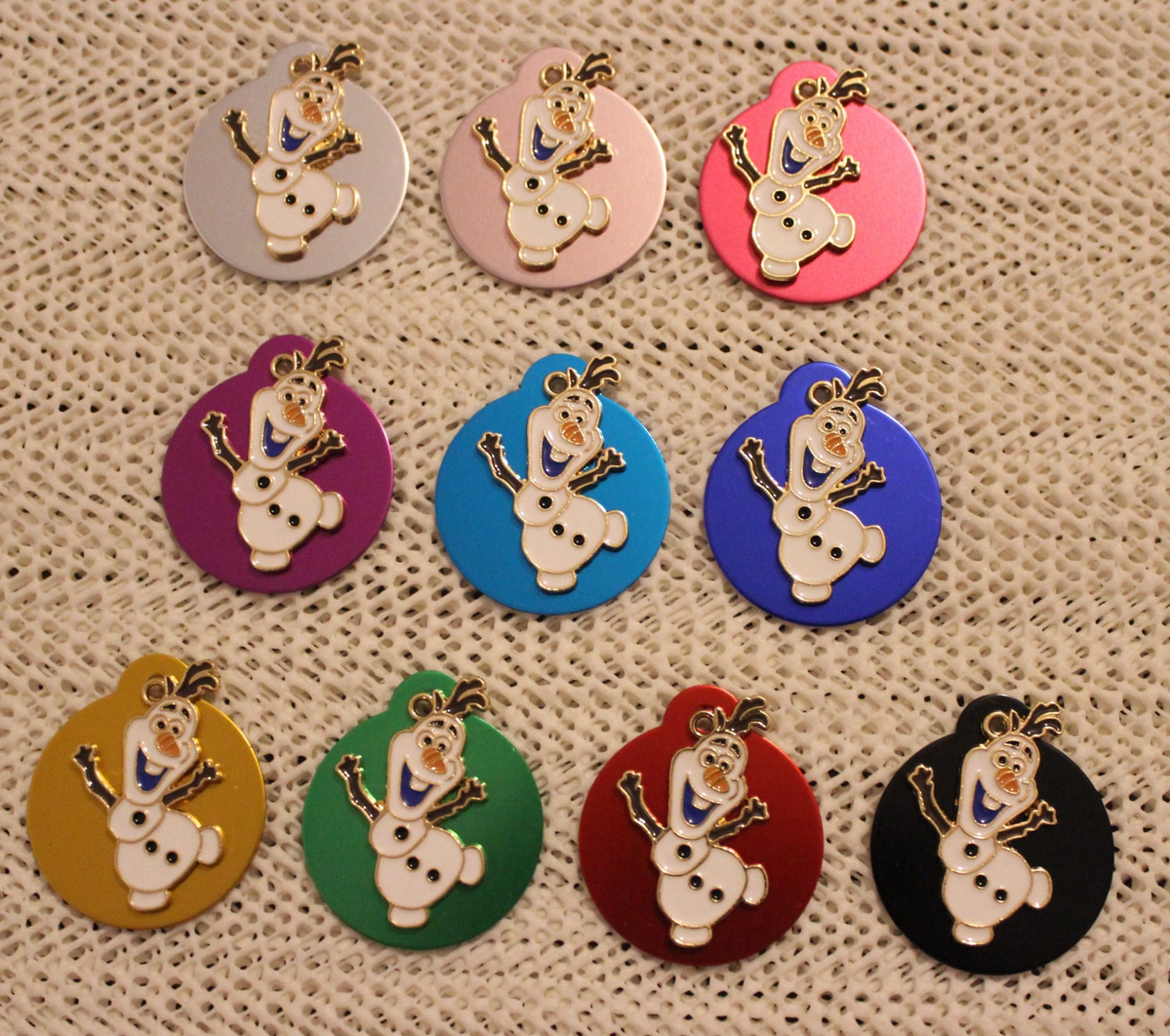 Pins redondos coloridos com personagem Olaf em relevo sobre malha bege