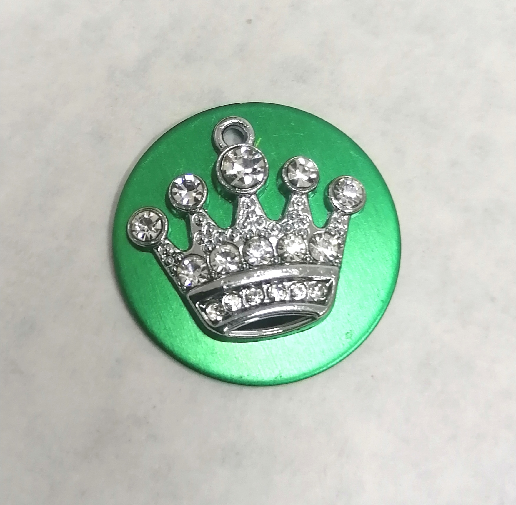 Botão verde com decoração de coroa prateada com pedras brilhantes