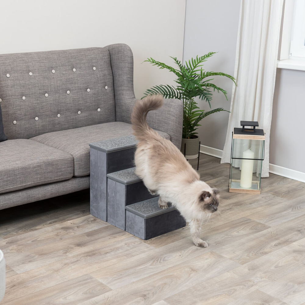 Escada cinza para gatos ao lado de sofá cinza, planta e lanterna