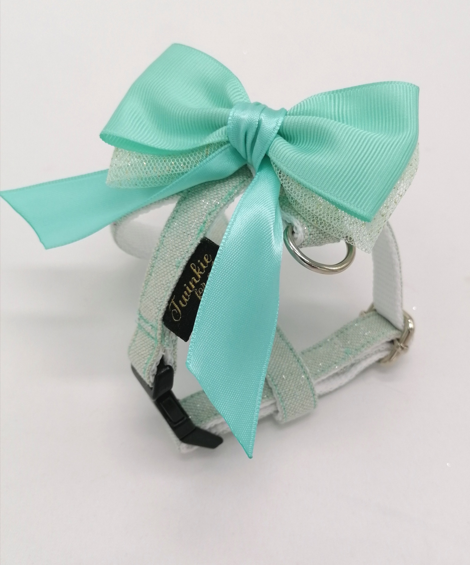 Coleira branca com laço azul-turquesa e etiquetas negras com texto dourado