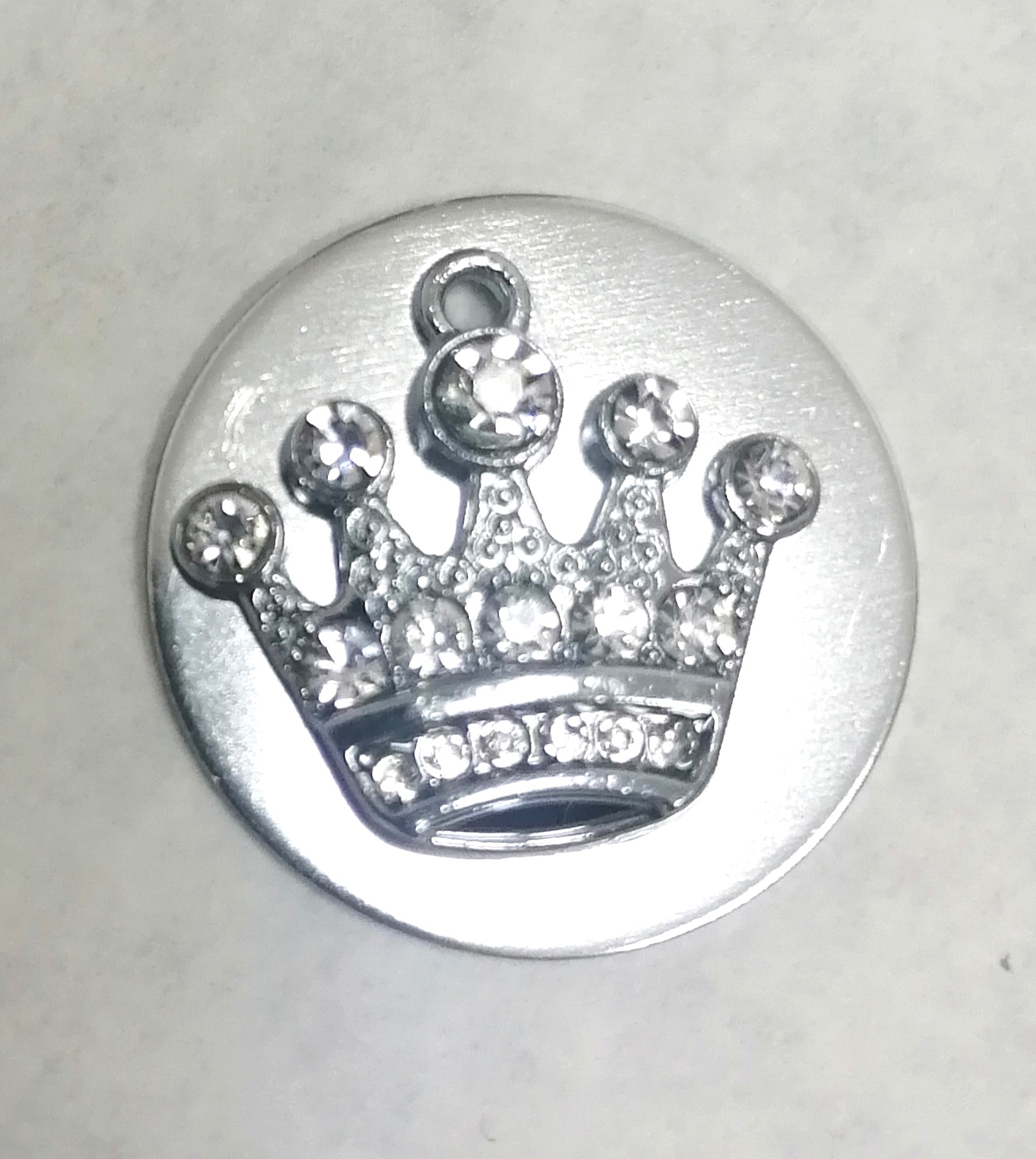 Disco metálico prateado com coroa e cristais brilhantes