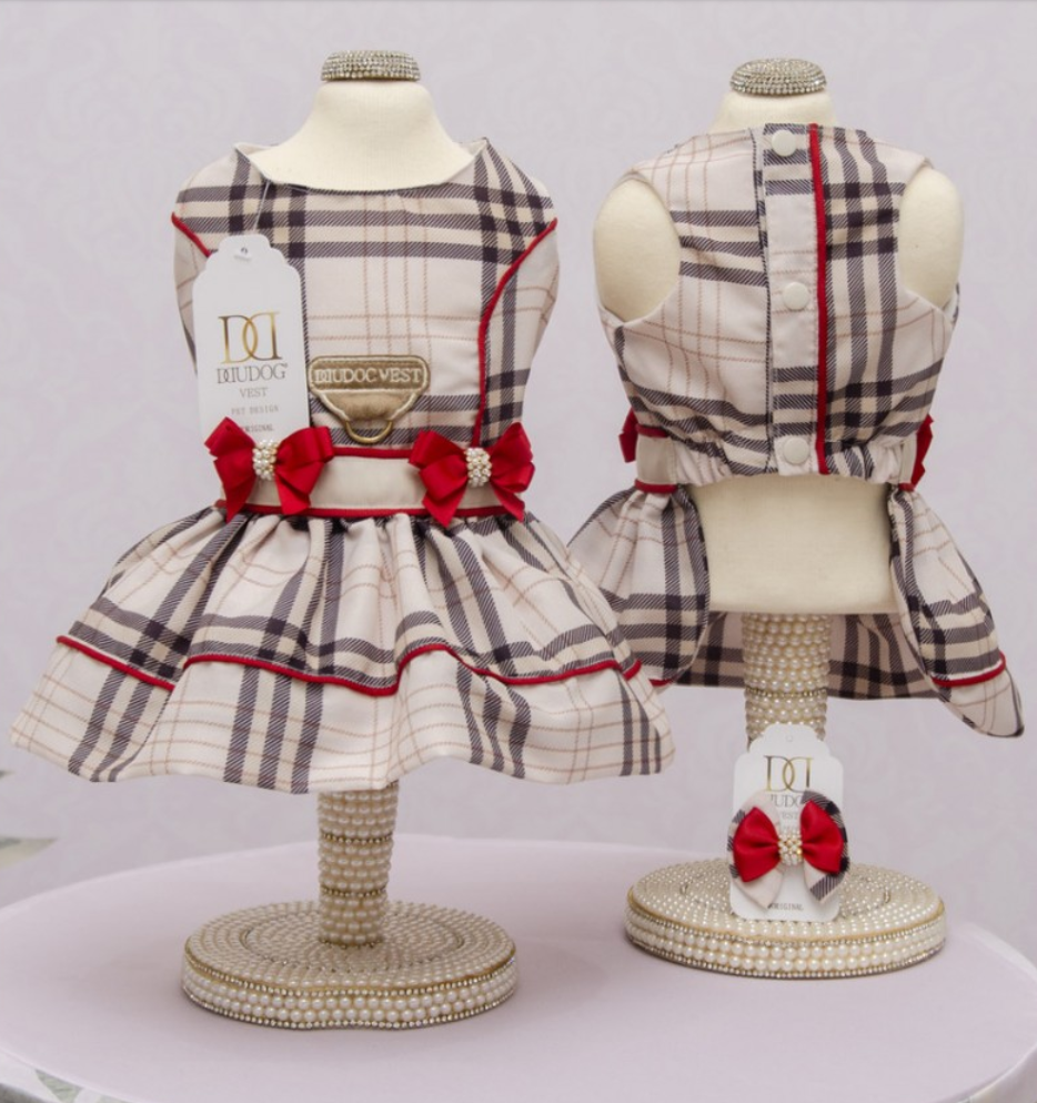 Vestido xadrez bege para cão com laços vermelhos em manequins decorativos.