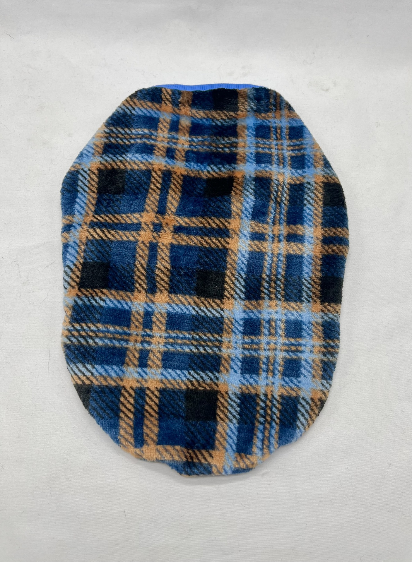 Almofada oval com padrão de xadrez azul, preto e bege sobre fundo branco