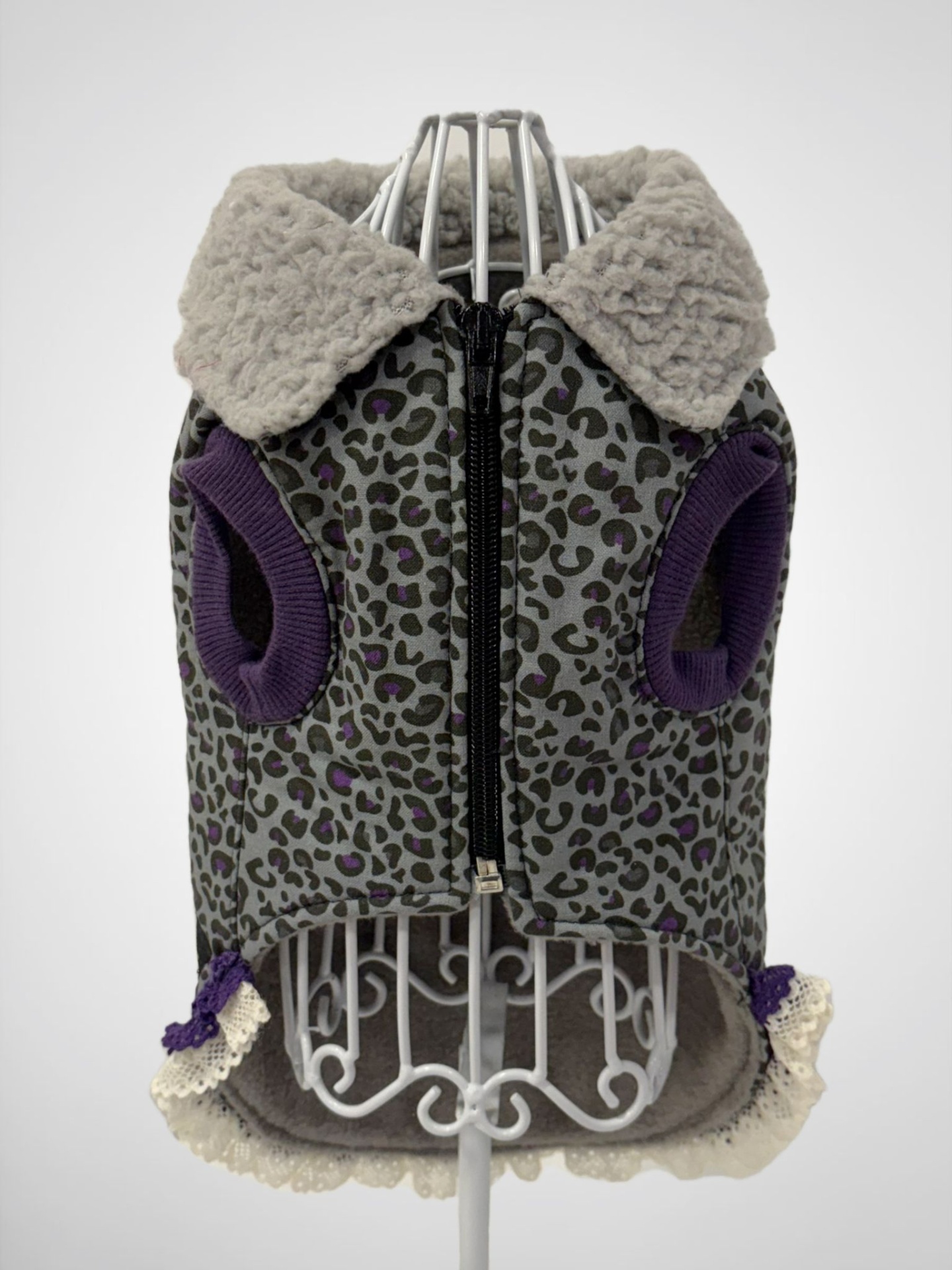 Casaco para cão com padrão de leopardo cinza e roxo, gola felpuda bege e acabamento de renda.