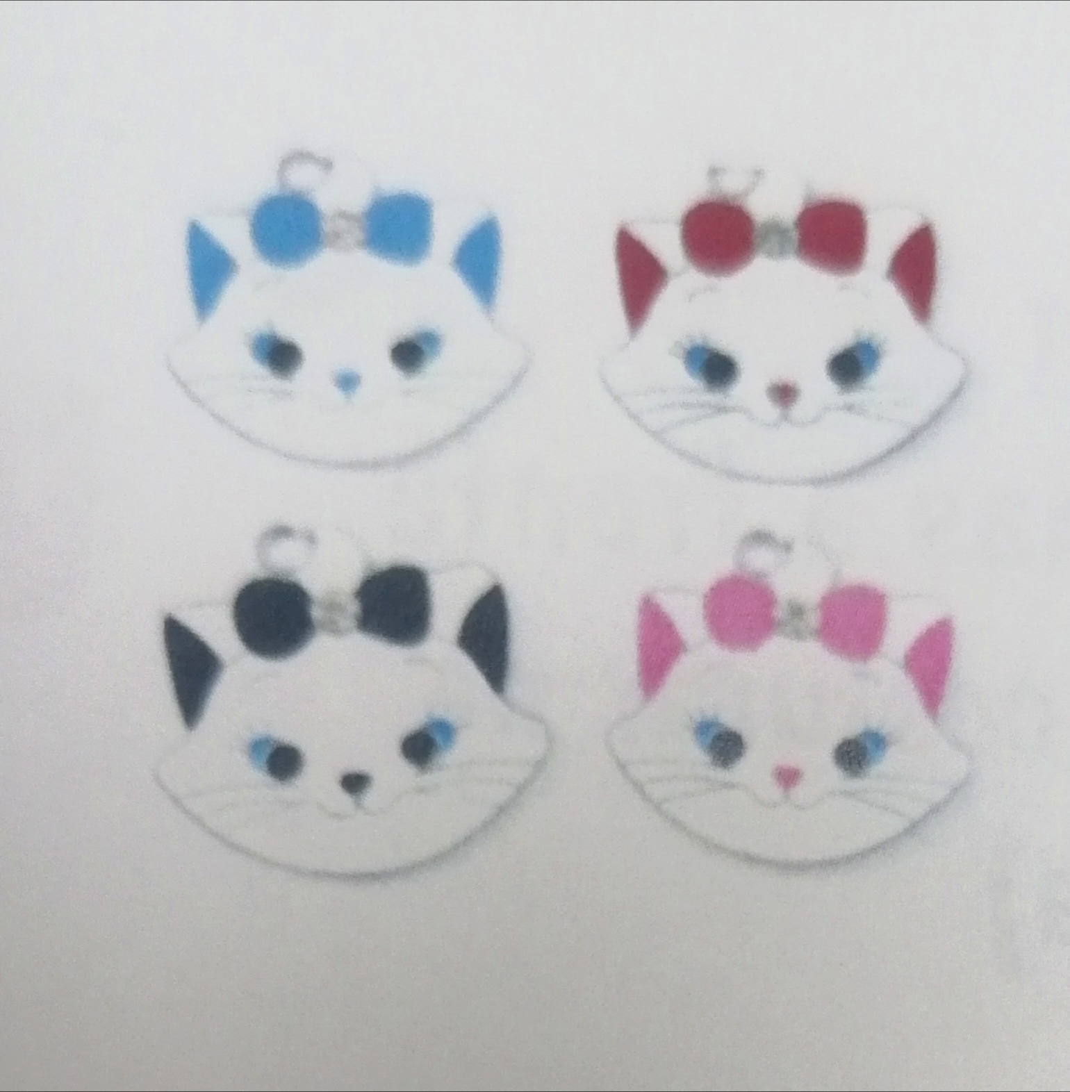 Quatro chaveiros de gato com laços coloridos sobre fundo branco