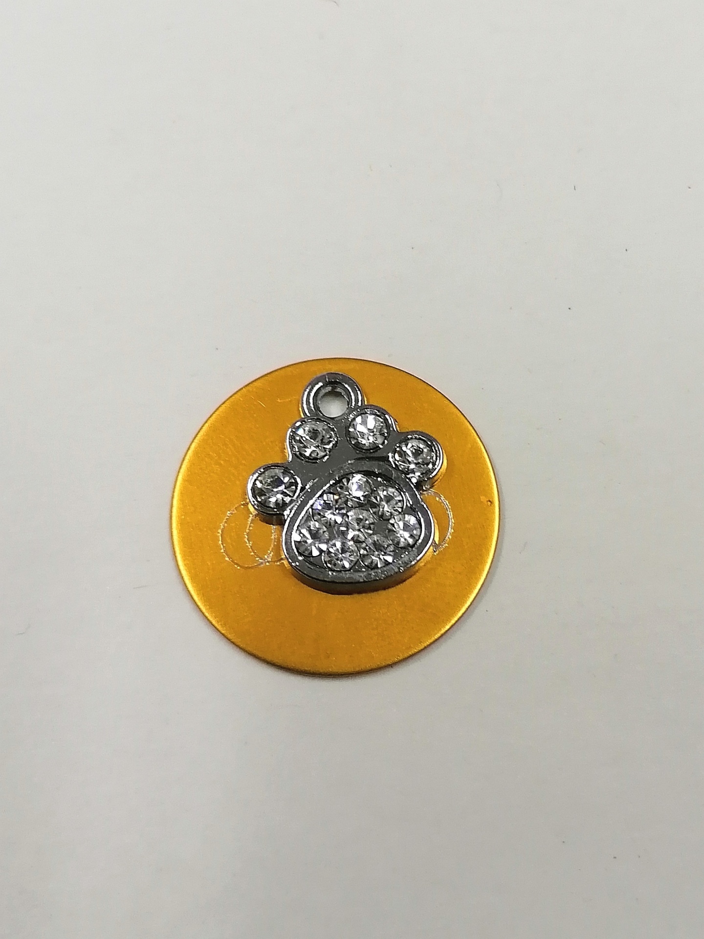 Pingente de pata com cristais sobre disco amarelo