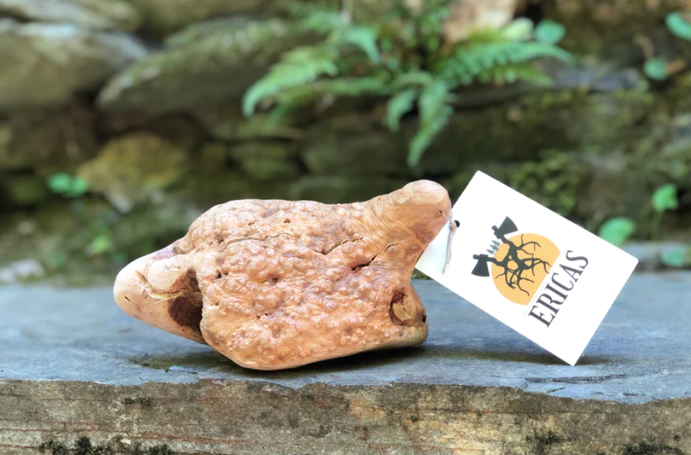 Pedra castanha clara com textura rugosa e etiqueta 'ERICAS' sobre superfície de madeira