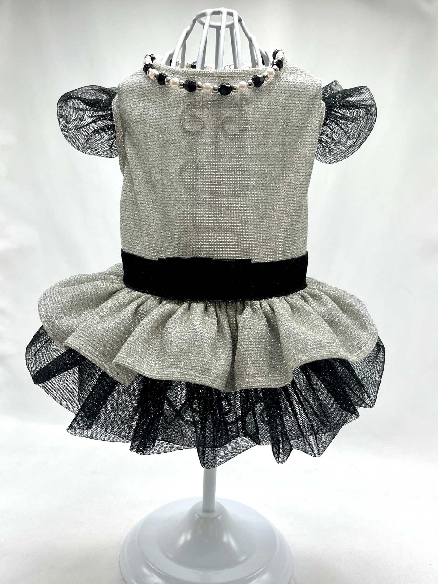 Vestido infantil branco com cintura preta e saia preta brilhante exibido num manequim branco