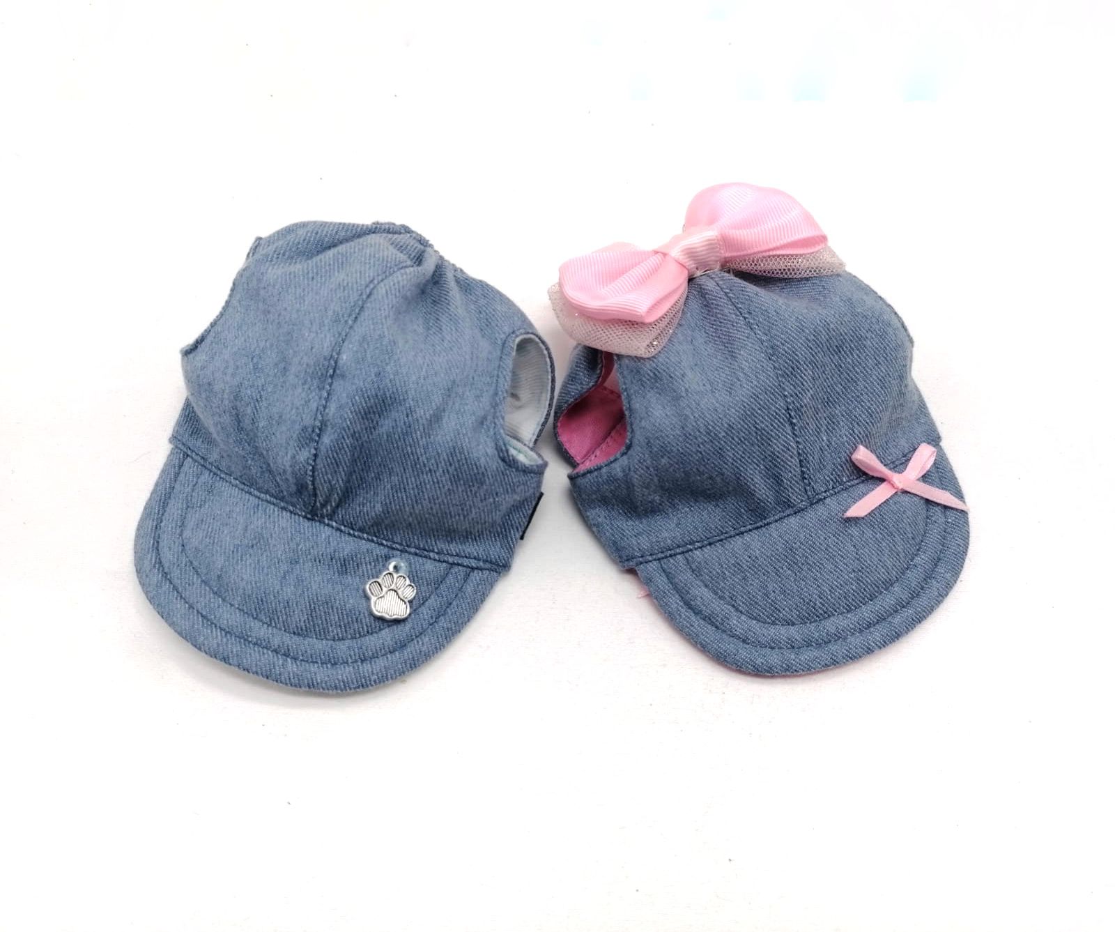 Dois bonés infantis de tecido jeans azul, um com laço rosa e outro com acessório metálico