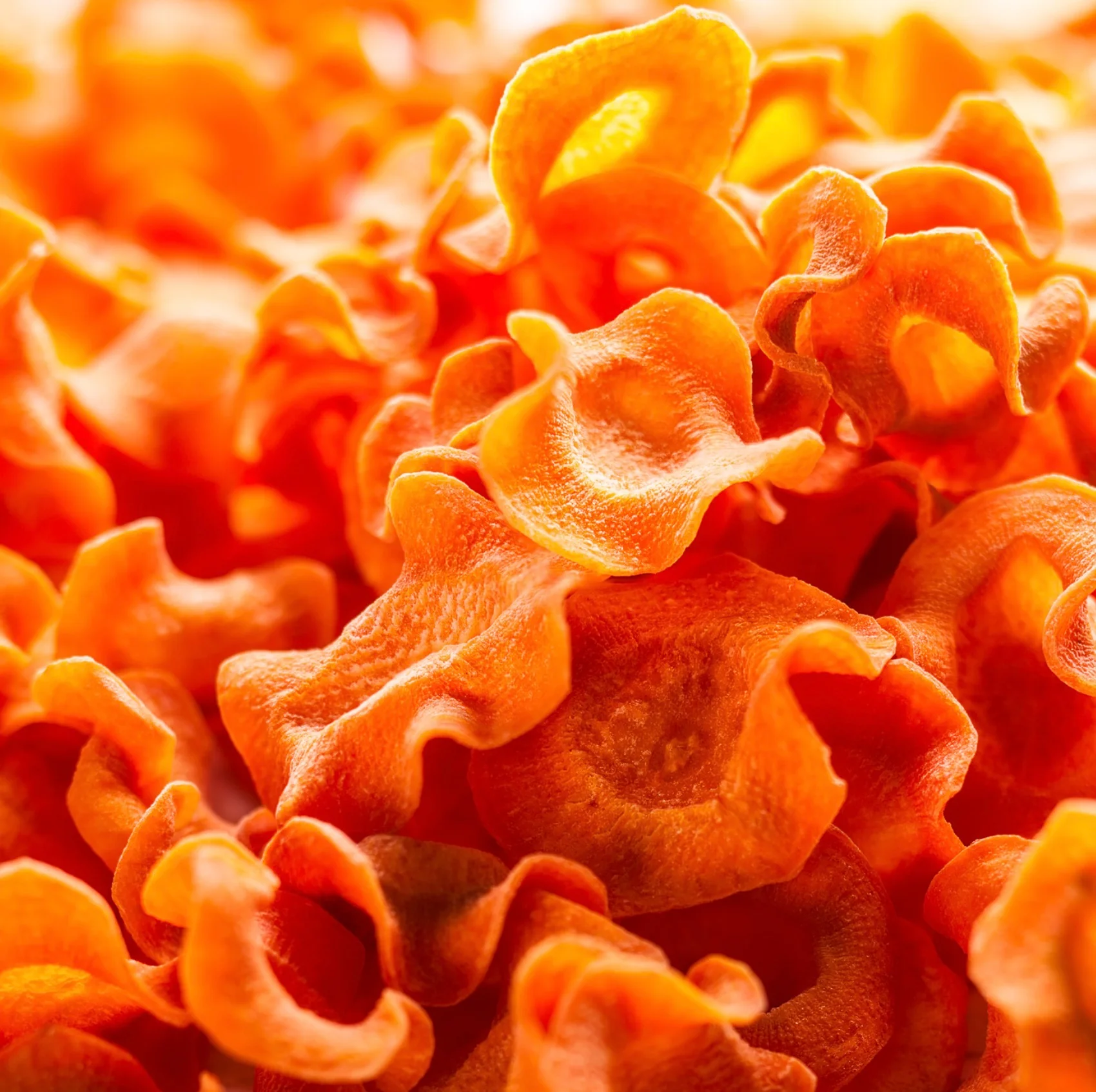 Batatas fritas finas e onduladas cor laranja em fundo branco