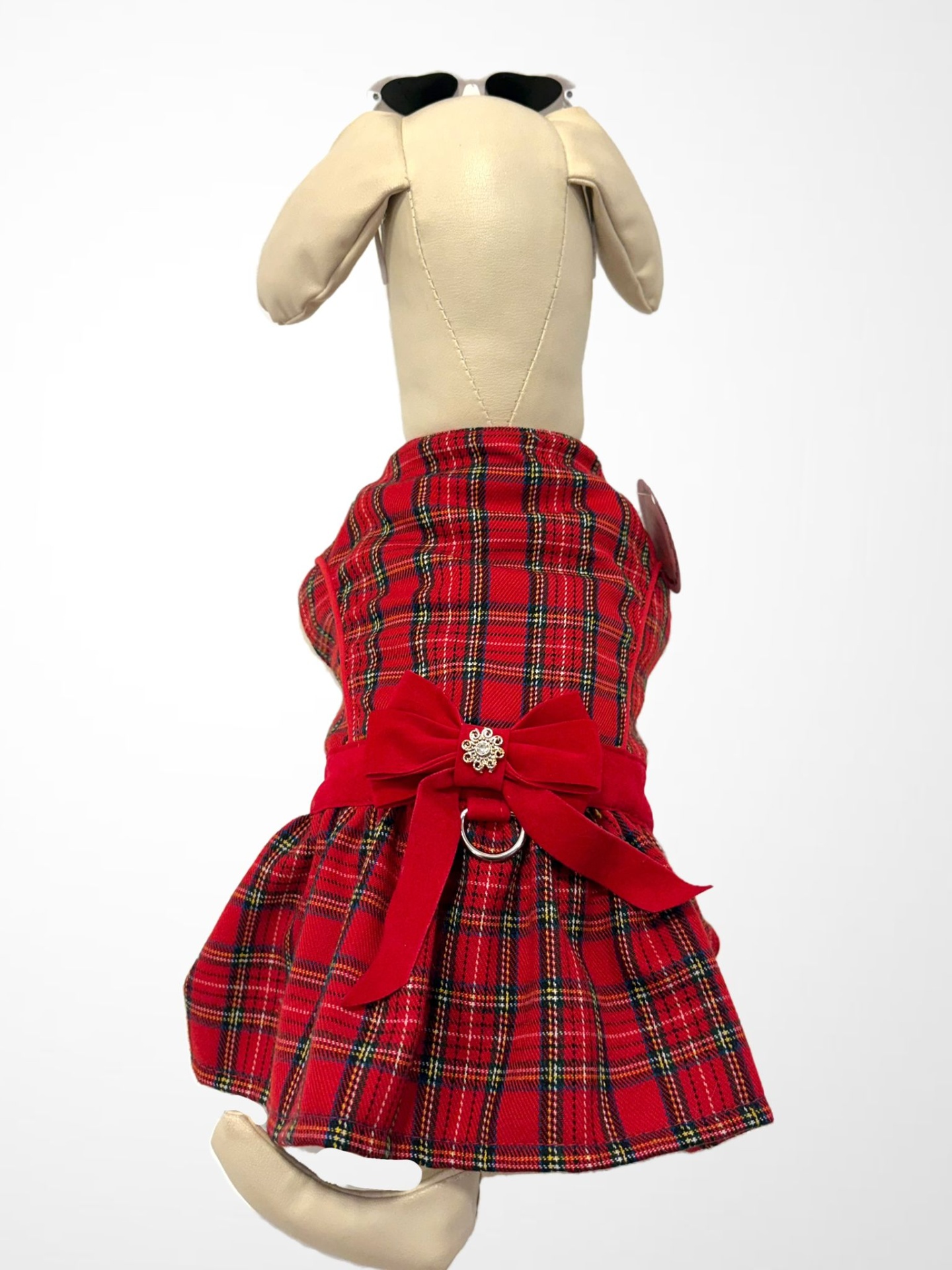 Roupa xadrez vermelha para cão com laço e pingente prateado, em manequim beige com óculos