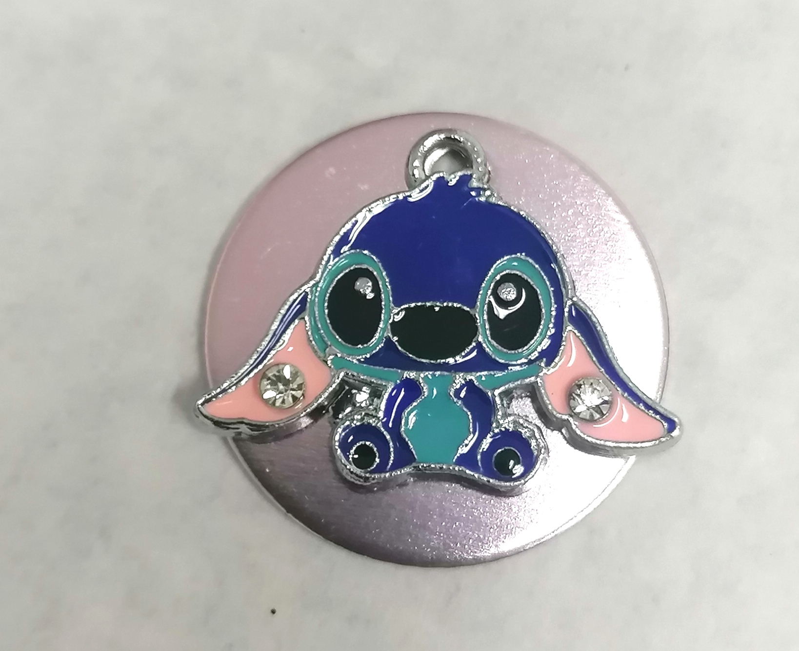 Pin metálico do personagem Stitch em fundo circular prateado e rosa com cristais