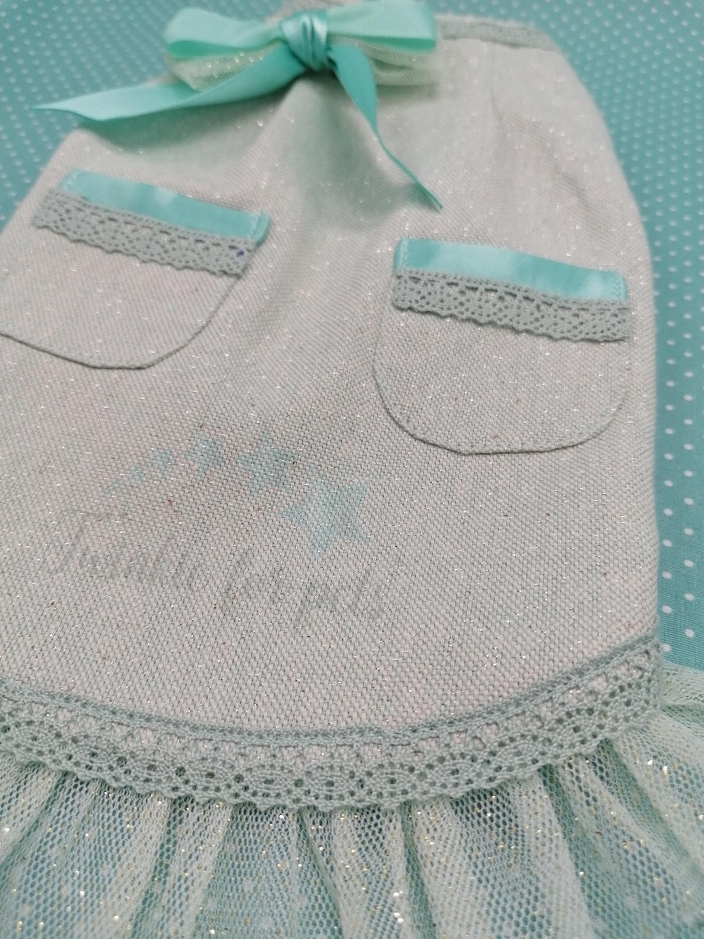 Vestido branco com brilho, bolsos com renda e fita azul, laço no decote e saia de tule azul claro.