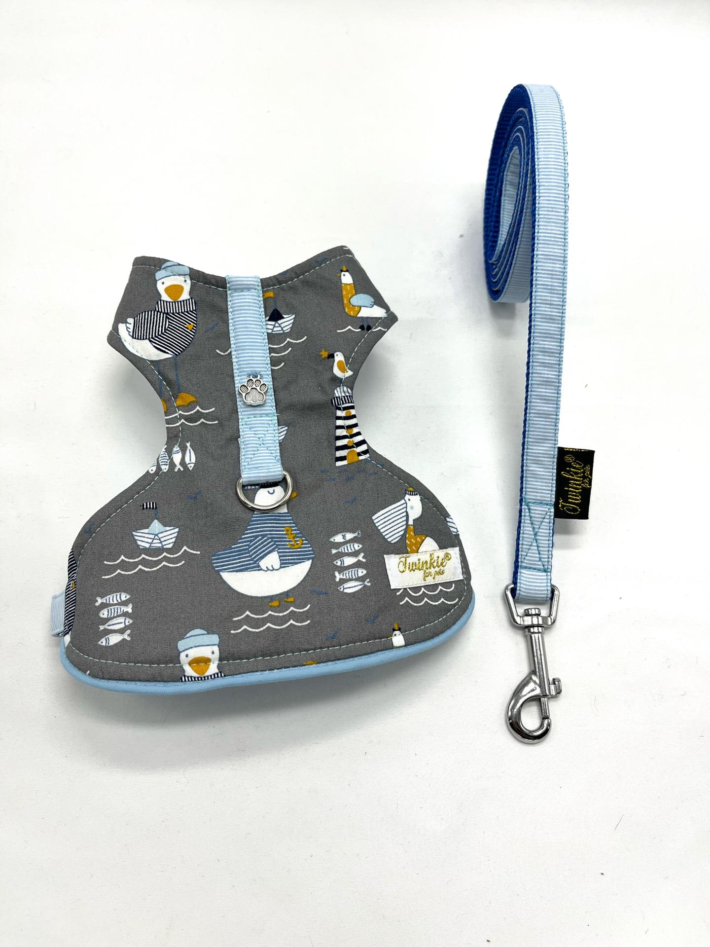 Colete peitoral cinza com padrão de barcos e gaivotas e trela azul clara