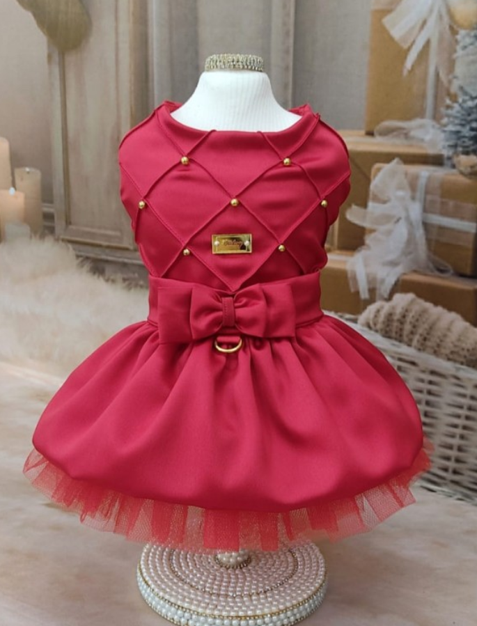 Vestido vermelho elegante com laço e detalhes dourados exposto num manequim