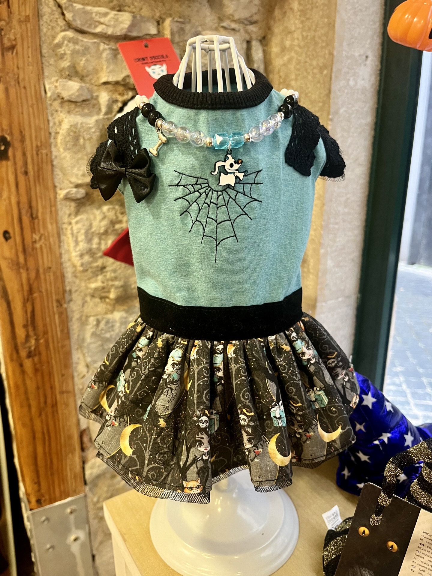 Vestido para cão verde água com detalhes pretos e padrão de personagens na saia.