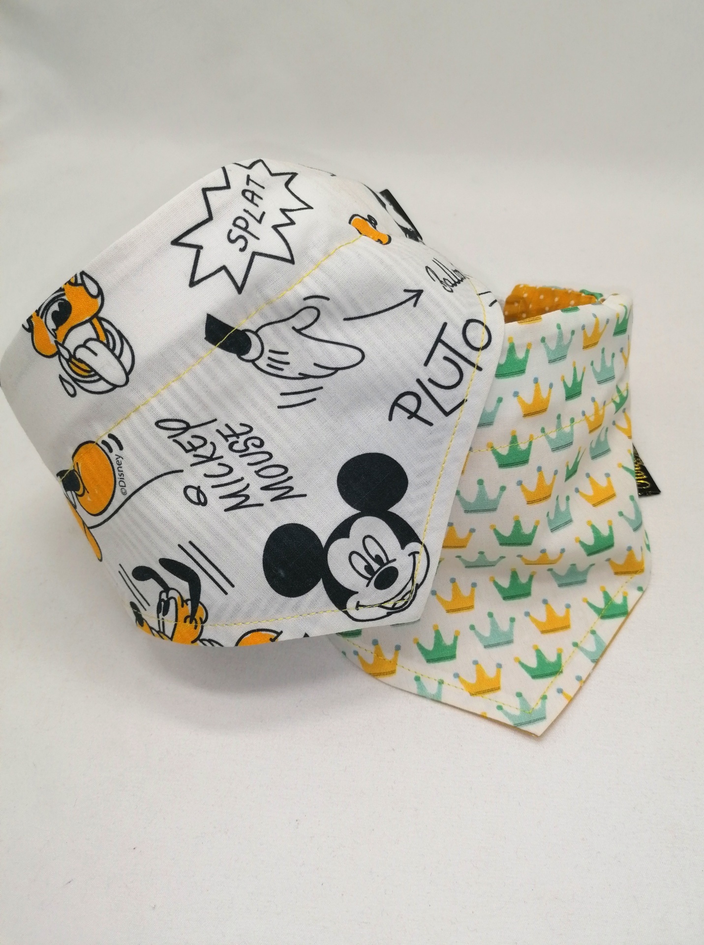 Babete de bebé com padrões da Disney e babete com padrão de coroas coloridas em tecido.