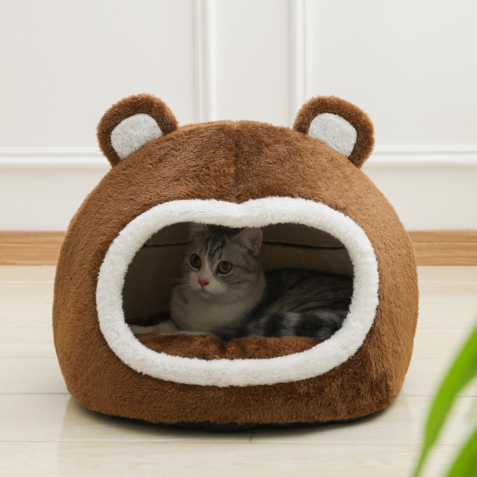 Cama para gato em forma de cabeça de urso castanha e branca com gato dentro
