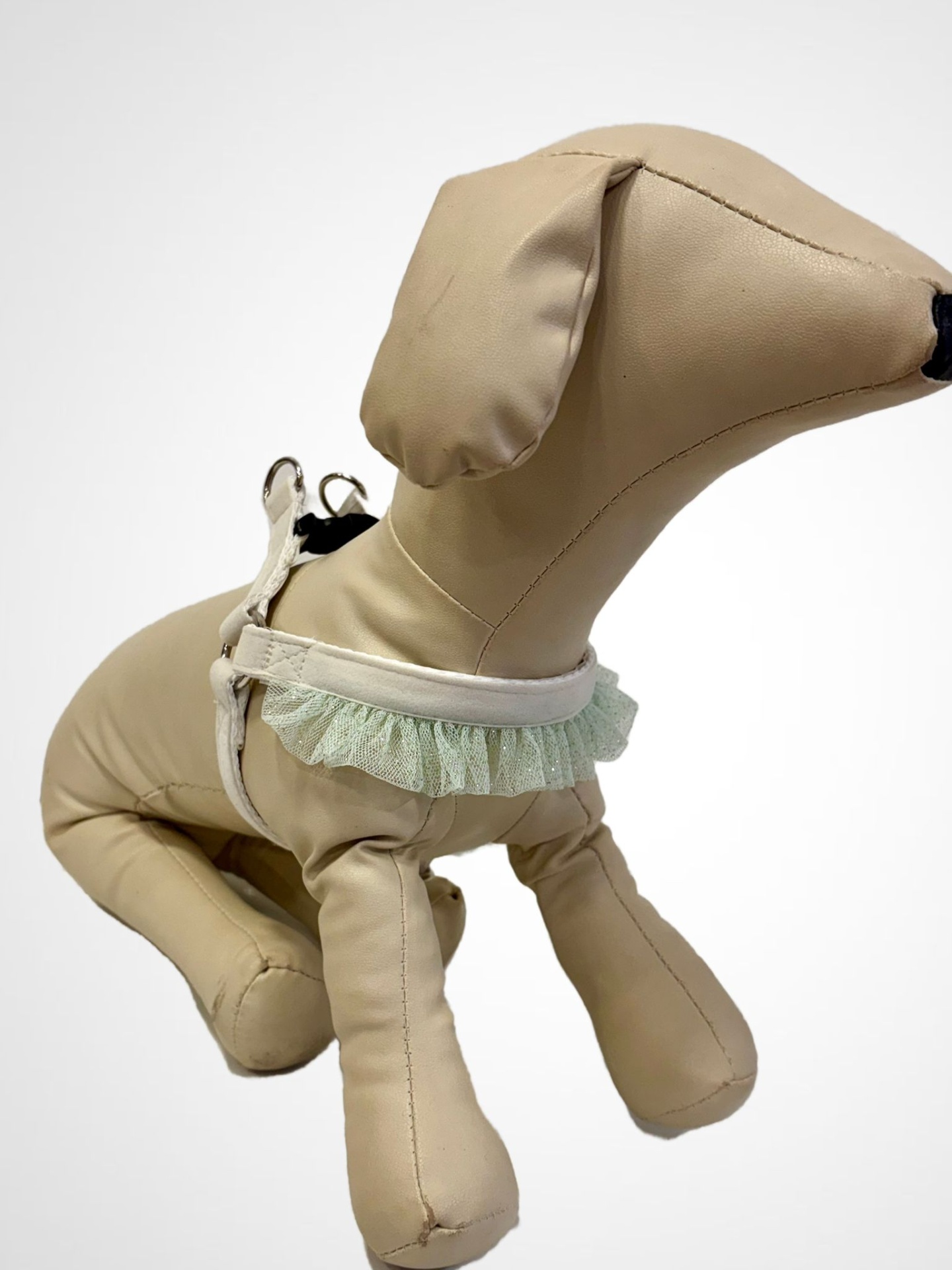 Estátua de cão bege em pele sintética com arnês branco e renda verde claro.