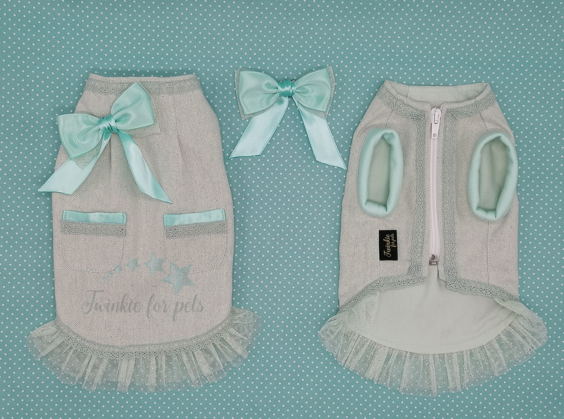 Dois casacos para cães cinzentos com detalhes azuis claros e dois laços decorativos sobre fundo azul com pontos