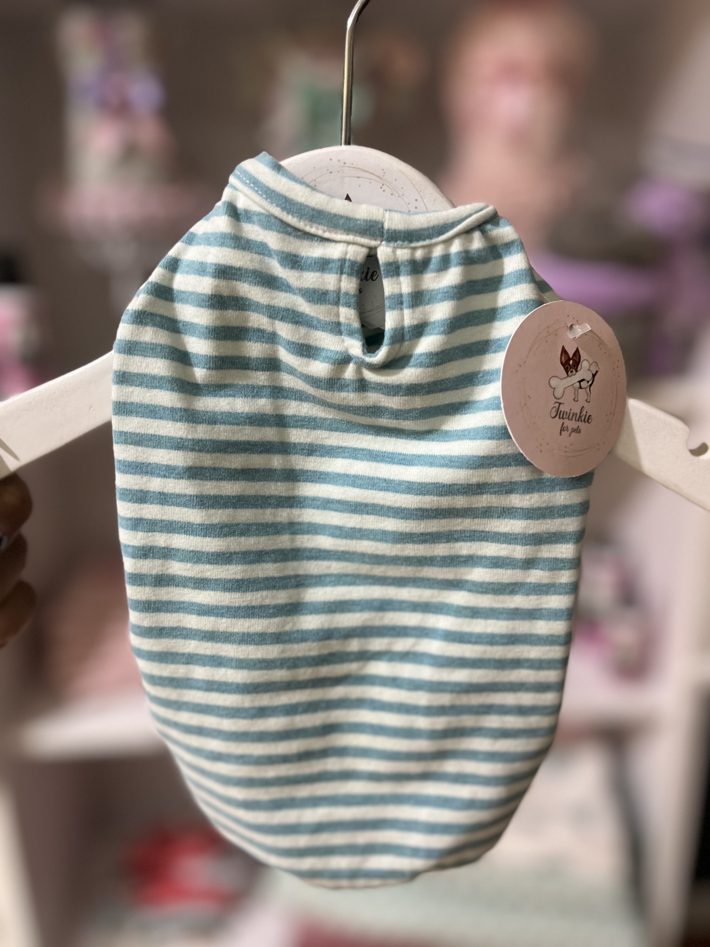 Roupa de tecido às riscas azul claro e branco para animal de estimação pendurada num cabide branco