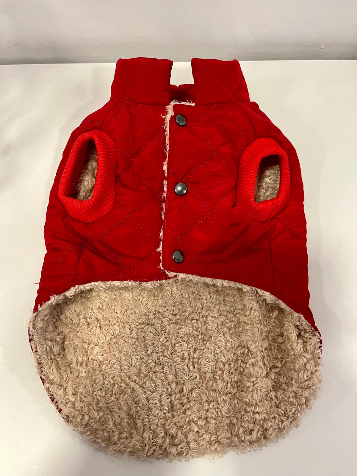 Casaco vermelho acolchoado para cão com interior peludo bege sobre superfície branca
