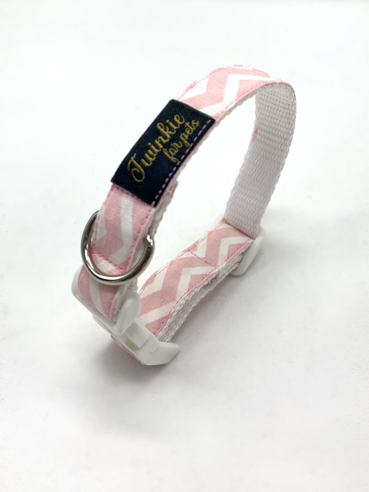 Coleira de cão rosa com padrão zig-zag e etiqueta preta com texto dourado