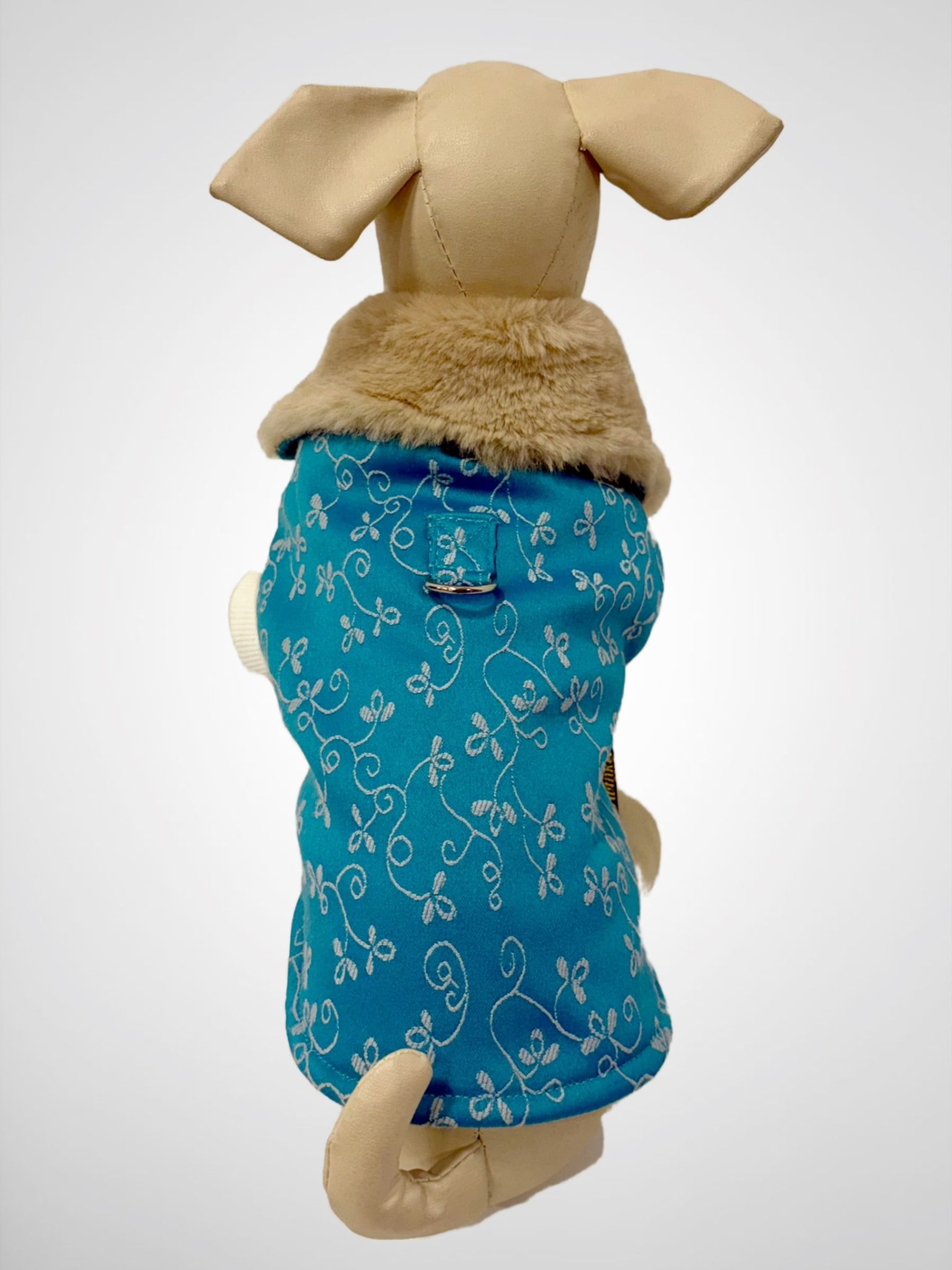 Casaco para cão azul com padrão floral branco e gola em pelo sintético bege num manequim canino.