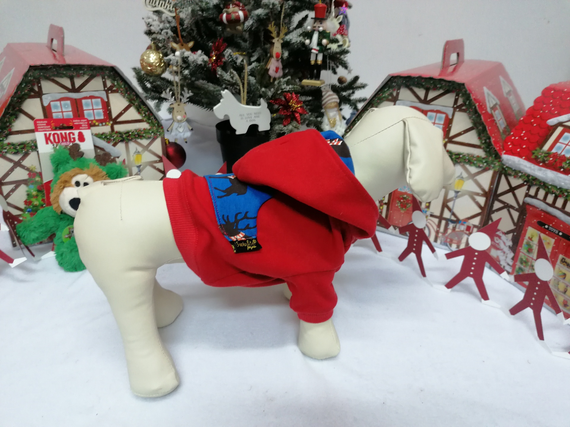 Mannequim de cão com roupa vermelha e cenário natalício