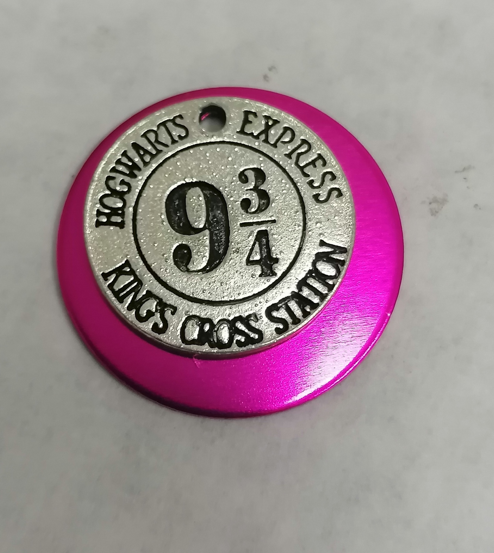 Chaveiro rosa metálico com emblema prateado e texto Hogwarts Express 9 3/4 King's Cross Station