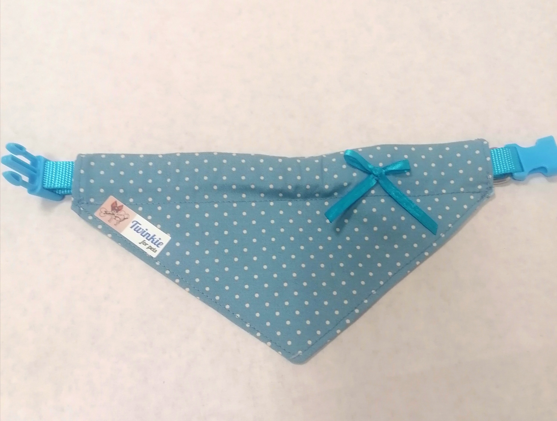 Bandana azul com pequenas estrelas brancas e laço azul, etiqueta Flexible, fecho ajustável