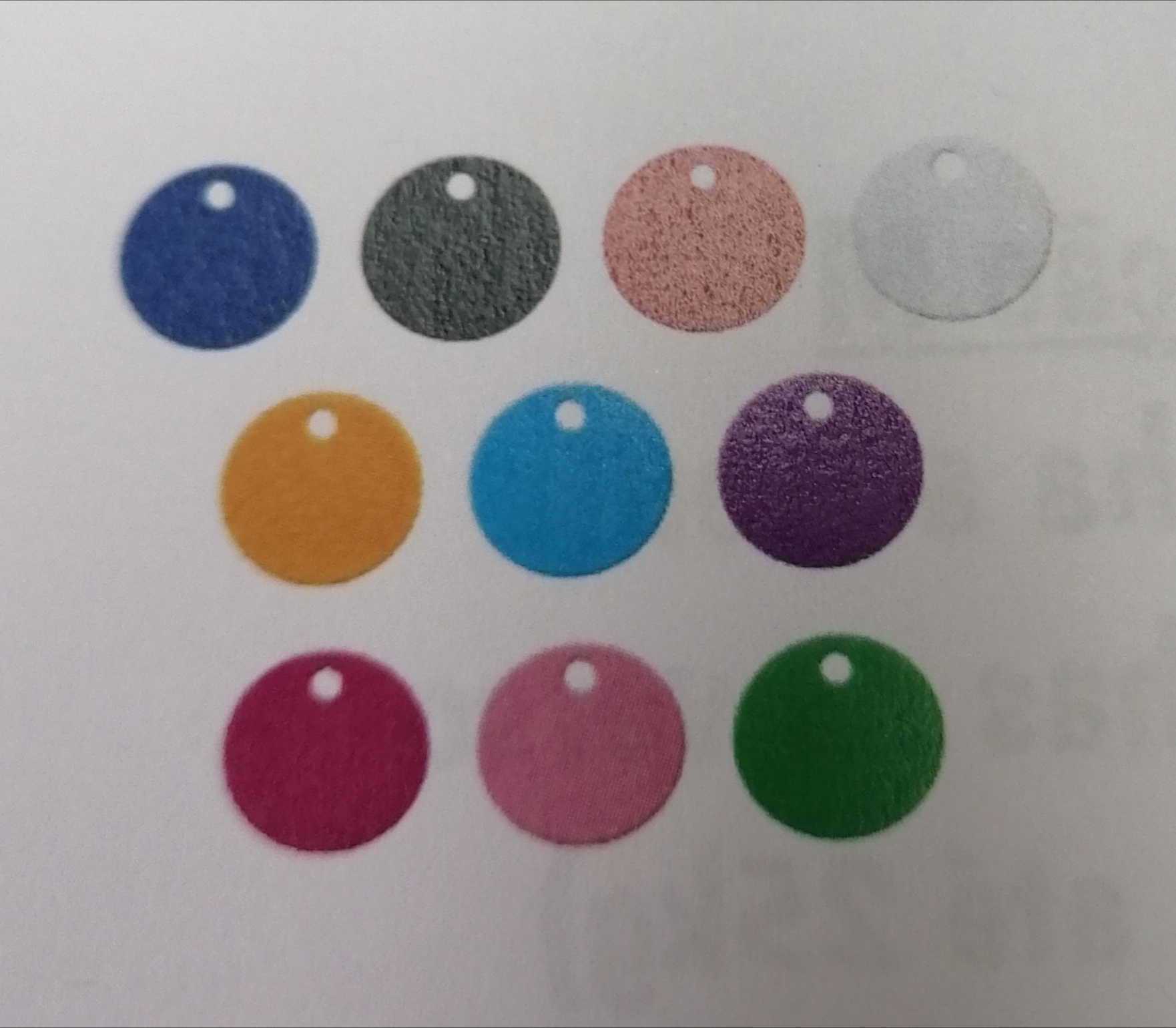 Nove etiquetas circulares coloridas com furo, dispostas em três filas sobre fundo branco.