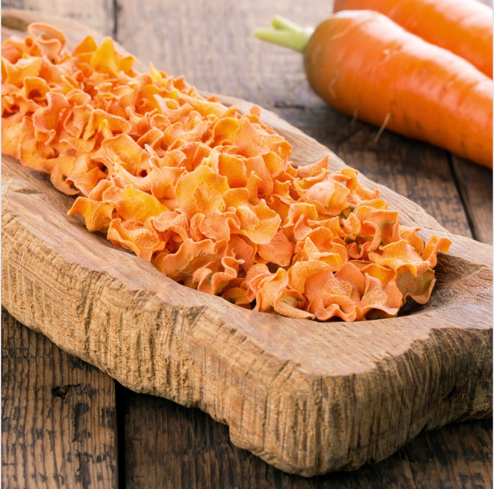 Massa laranja ondulada e cenouras numa tábua de madeira