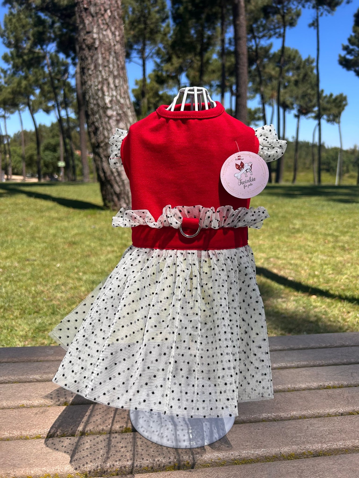 Vestido para cão vermelho com saia branca de bolinhas negras em manequim ao ar livre